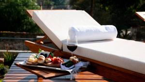 a plate of food and a glass of wine on a bed at Kkala Boutique Hotel in Salta