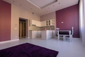 a kitchen with purple walls and a table and chairs at Hotel Ankavi in Szeged