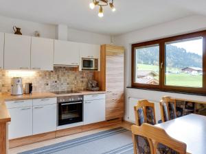 クライナルにあるLovely Apartment in Kleinarl near Ski Areaの白いキャビネットとテーブル付きのキッチン