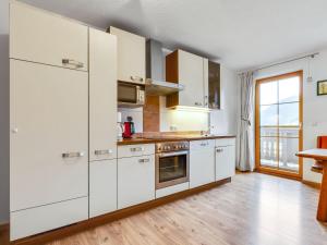 a kitchen with white cabinets and a wooden floor at Spacious Villa with Sauna in Mittersill in Mittersill