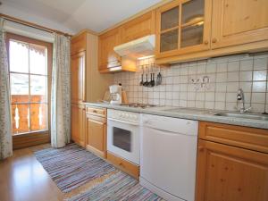 a kitchen with wooden cabinets and a white dishwasher at Apartment in Embach Austria near ski area in Embach