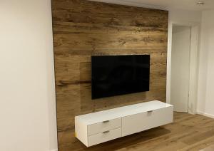 a living room with a tv on a wooden wall at Pia am See - Bio Design Appartement in Bad Wiessee