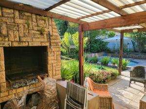 an outdoor patio with a stone fireplace and a wooden pergola at The Lion's Den in George