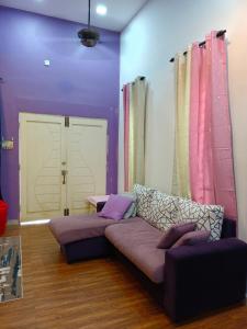 a living room with a couch and purple walls at HOMESTAY D'TEPIAN CASA, BANDAR SERI IMPIAN KLUANG in Kluang