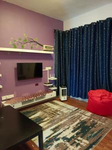 een woonkamer met een tv en blauwe gordijnen bij HOMESTAY D'TEPIAN CASA, BANDAR SERI IMPIAN KLUANG in Kluang