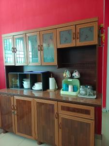 een keuken met houten kasten en een magnetron bij HOMESTAY D'TEPIAN CASA, BANDAR SERI IMPIAN KLUANG in Kluang