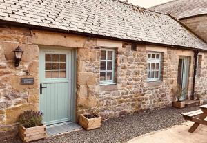 Cabaña de piedra con puerta azul y ventanas en Elishaw Farm Holiday Cottages en Otterburn