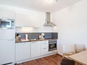 biała kuchnia z białymi szafkami i stołem w obiekcie Apartment in Saalfelden near Ski Slopes w mieście Saalfelden am Steinernen Meer