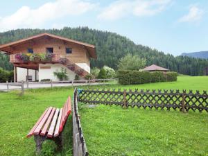 a wooden bench in a field next to a building at Charming Apartment with Shared Pool in Waidring Tyrol in Waidring