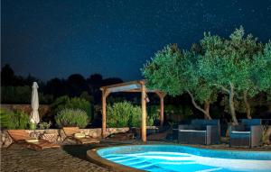 a pool at night with chairs and a gazebo at Lovely Home In Stari Grad in Basina
