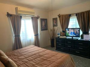 a bedroom with a bed and a television on a dresser at Quinta Campestre Los Encinos in Santiago