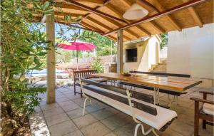 un patio con mesa de madera, bancos y sombrilla en 8 Bedroom Gorgeous Home In Kozino, en Kožino