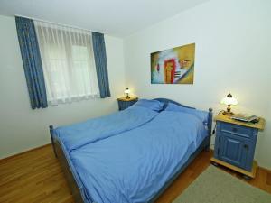 1 dormitorio con cama azul y mesa con lámpara en Apartment at the ski lift in Brand in Vorarlberg, en Brand