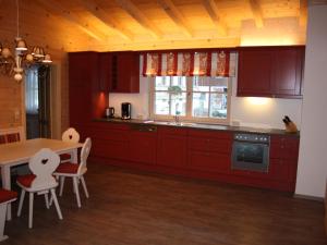 cocina con armarios rojos, mesa y sillas en Spacious Apartment with Sauna in Leogang, en Leogang