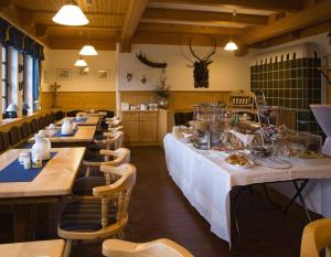 un restaurante con una mesa larga con mesas y sillas blancas en Hotel Hembacher Hof, en Rednitzhembach