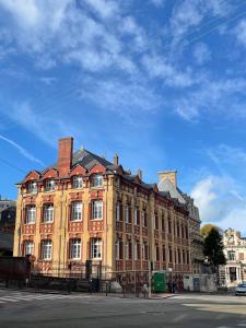 een groot gebouw op een straat met een blauwe lucht bij "Curiosités", place de parking privative, centre ville in Dieppe