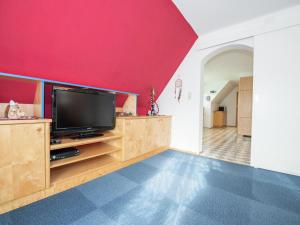 salon z telewizorem i czerwoną ścianą w obiekcie Apartment in Tröpolach near Nassfeld Gondola w mieście Tröpolach +18 zdjęć