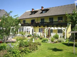 a yellow house with a balcony and a yard at Charming Apartment in Feld am See 100 m from Lake in Feld am See