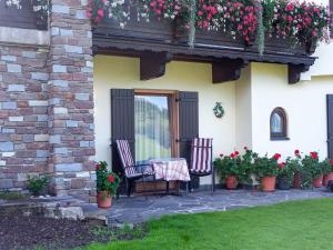 伊特爾的住宿－Apartment in Tyrol 100 m to the mountain railway，庭院配有两把椅子和一张桌子,种有鲜花