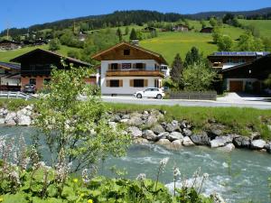 a river in front of a building with a house at Fantastic chalet in Saalbach Hinterglemm Salzburgerland for 22 people in Saalbach Hinterglemm