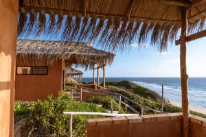 una casa sulla spiaggia con tetto di paglia e l'oceano di Bela Flor Beach Front Apartments a Inhambane