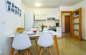 a kitchen with a table and four white chairs at Nice Apartment In Postira With Wifi in Postira