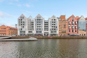a group of buildings next to a body of water at Downtown Apartments Riverside Granaria in Gdańsk
