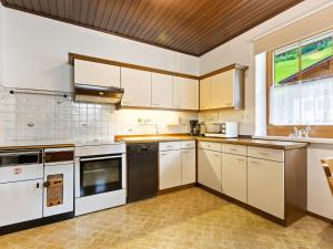 a kitchen with white cabinets and a large window at Spacious Apartment in Grossarl with Garden in Grossarl