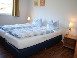 Schlafzimmer mit einem Bett mit blauer und weißer Bettwäsche und Kissen in der Unterkunft Apartment in Kaprun near ski lift in Kaprun