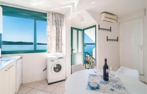 uma cozinha com uma máquina de lavar roupa e uma mesa com copos de vinho em Lovely Apartment In Kastel Gomilica With Kitchen em Kaštela