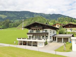 ein großes weißes Haus mit einem Hügel im Hintergrund in der Unterkunft Lush Apartment in Hollersbach im Pinzgau with Terrace in Hollersbach im Pinzgau