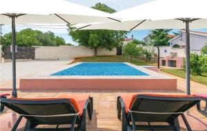 a swimming pool with two chairs and an umbrella at Amazing Home In Marcana With House A Panoramic View in Divšići