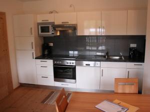 a kitchen with white cabinets and a stove top oven at Apartment with Sauna near Ski Slopes in Mittersill in Hollersbach im Pinzgau