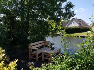 un banco de madera sentado frente a un estanque en Vliet Huis en Medemblik