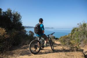 a man riding a bike on a trail near the ocean at Pigna Felice Punta Ala in Punta Ala