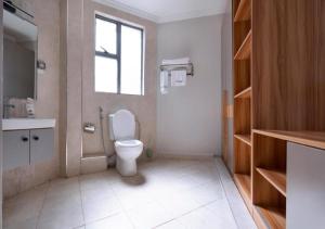 a bathroom with a toilet and a sink and a window at Raha Suites - Westlands 