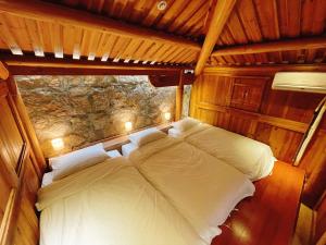 a bed in a room with a stone wall at 大宅三院青年旅舍 背包客棧 in Beigan
