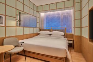 a bedroom with a bed and a window and a table at The Shàng by Artyzen Qiantan Shanghai in Shanghai +43 photos