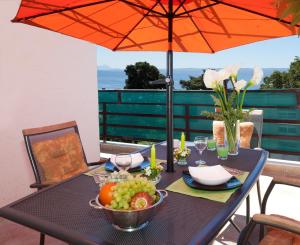 a table with a bowl of fruit and an umbrella at Apartments Beautiful Sandy Beach in Split