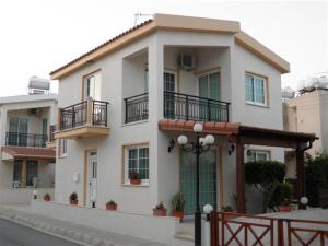 a large white house with balconies on a street at Philippou Beach Villas & Apartments in Larnaka