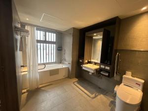a bathroom with a tub and a sink and a toilet at Watermark Hotel Kaohsiung Main Station in Kaohsiung