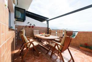 een tafel en stoelen op een balkon met een televisie bij Vista Faro Sardina in Las Palmas de Gran Canaria