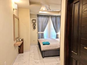 a small bedroom with a bed and a window at Tranquil & Delightful 1 Bed Apt In Bahria Town in Rawalpindi
