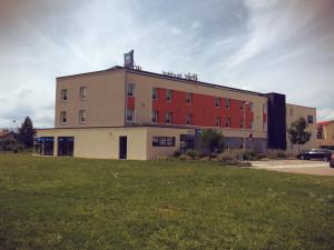 a large building with a grass field in front of it at Ibis Budget Roanne Hôtel in Roanne