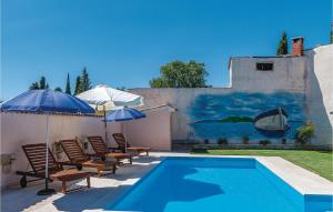 una piscina con sedie e ombrelloni accanto a una casa di Stunning Home In Divsici With Kitchen a Divšići