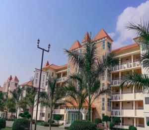 un gran edificio con palmeras delante en Happy City Golf & Resort, en Chiang Rai