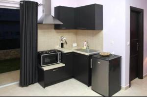 a small kitchen with black cabinets and a microwave at Spilios Apartment in Nafplio