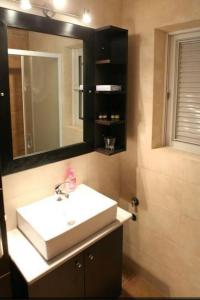 La salle de bains est pourvue d'un lavabo blanc et d'un miroir. dans l'établissement Spilios Apartment, à Nauplie