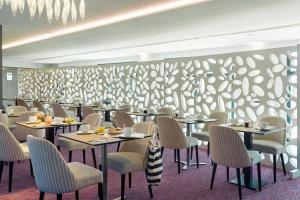 un restaurant avec des tables et des chaises et un mur à motifs dans l'établissement Thalasso Concarneau Spa Marin Resort, à Concarneau
