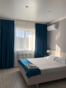 1 dormitorio con 1 cama con cortinas azules y ventana en HANYM HOTEL en Atyraū